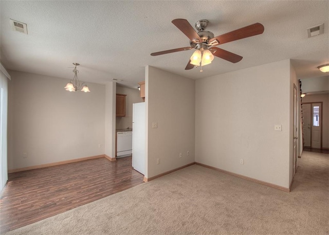 unfurnished room with a textured ceiling, ceiling fan with notable chandelier, and light hardwood / wood-style floors