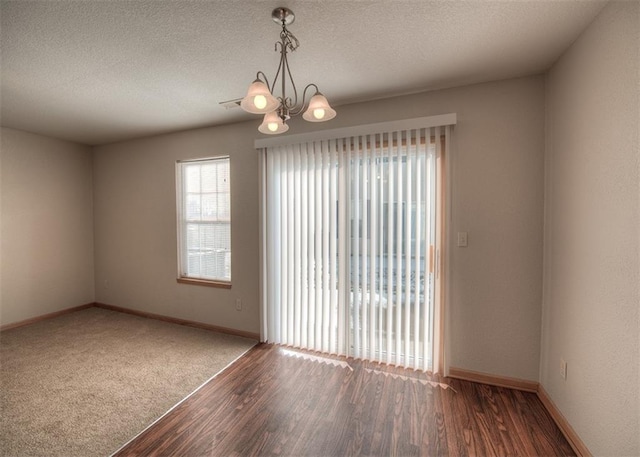 spare room with wood-type flooring, an inviting chandelier, and a textured ceiling