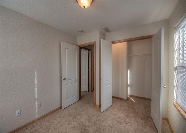 unfurnished bedroom featuring light colored carpet and a closet