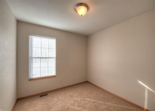 carpeted spare room with a textured ceiling