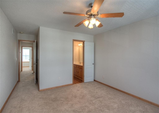 unfurnished bedroom with ensuite bath, light carpet, ceiling fan, and a textured ceiling