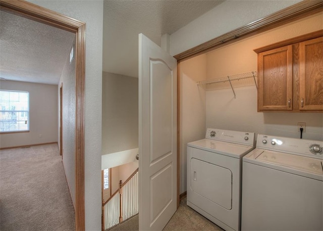 washroom with light carpet, a textured ceiling, cabinets, and washer and clothes dryer