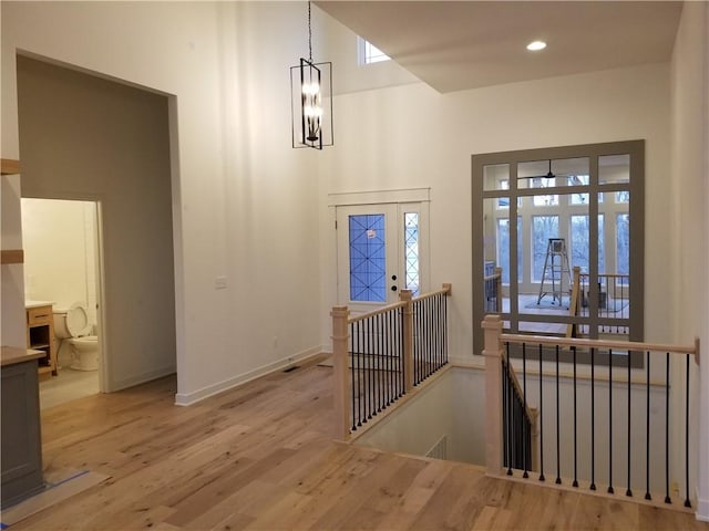 entrance foyer with light wood finished floors, baseboards, recessed lighting, a high ceiling, and an inviting chandelier