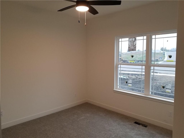 empty room with visible vents, carpet, baseboards, and ceiling fan