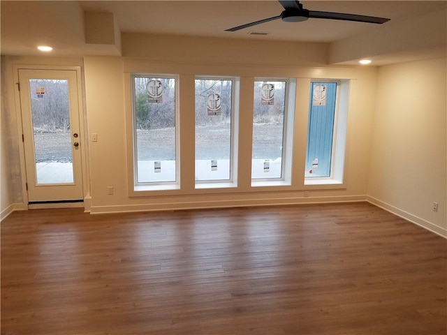 interior space with a ceiling fan, baseboards, and wood finished floors