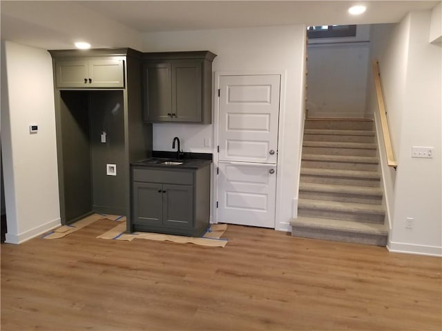 kitchen with dark countertops, light wood-style flooring, baseboards, and a sink