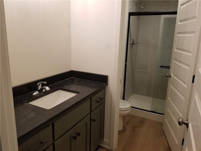 bathroom with a shower with door, vanity, wood-type flooring, and toilet