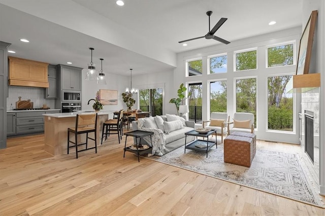 14574 Aurora Ln, Basehor, KS 66007 - living room featuring a ceiling fan, light wood-style floors, recessed lighting, a glass covered fireplace, and a high ceiling