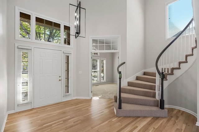 foyer entrance with a high ceiling, hardwood / wood-style flooring, and a notable chandelier