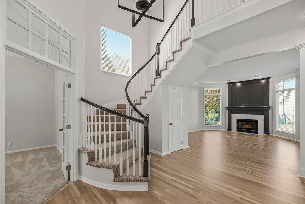 staircase featuring a fireplace, wood-type flooring, and a towering ceiling