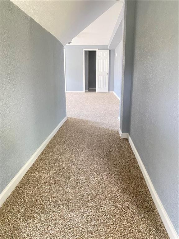 corridor with vaulted ceiling and carpet