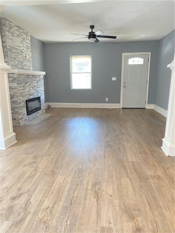 unfurnished living room with light wood-type flooring, a fireplace, and ceiling fan