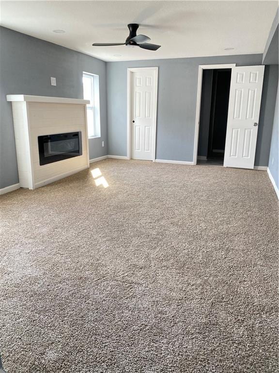 unfurnished living room featuring ceiling fan and carpet flooring