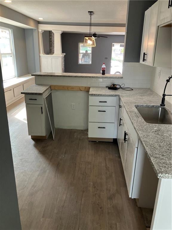 kitchen with a wealth of natural light, white cabinets, kitchen peninsula, and decorative light fixtures