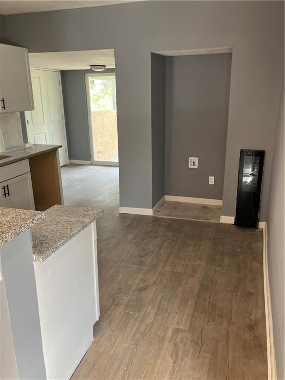 kitchen with white cabinets, light stone countertops, and light hardwood / wood-style floors