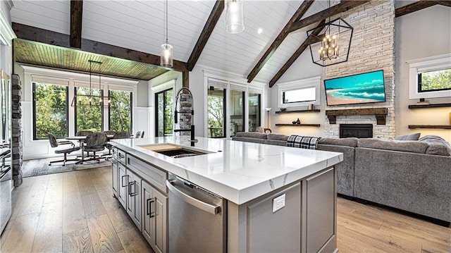 kitchen featuring a center island with sink, pendant lighting, dishwasher, a notable chandelier, and light hardwood / wood-style floors