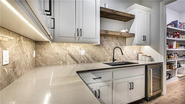 kitchen featuring light hardwood / wood-style flooring, backsplash, wine cooler, sink, and white cabinets