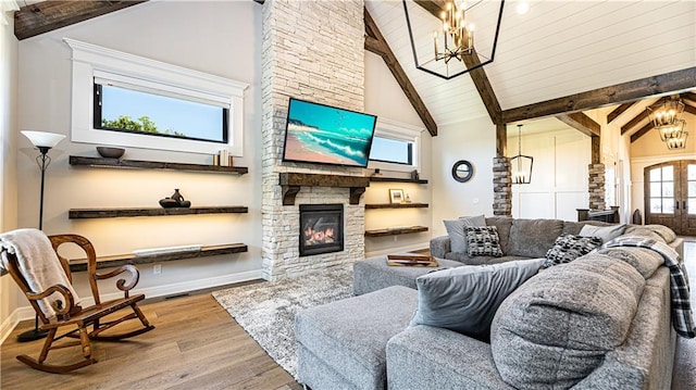 living room with a notable chandelier, wood-type flooring, beam ceiling, and a fireplace