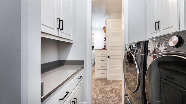 laundry room with washer and clothes dryer, light colored carpet, and cabinets