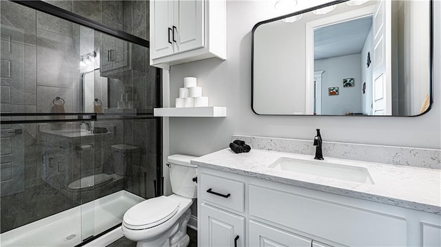 bathroom with vanity, toilet, and a shower with door