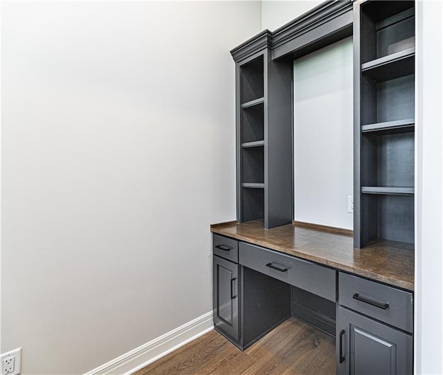 office with built in desk and dark hardwood / wood-style flooring