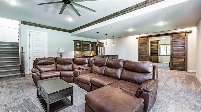 carpeted living room featuring a barn door and ceiling fan