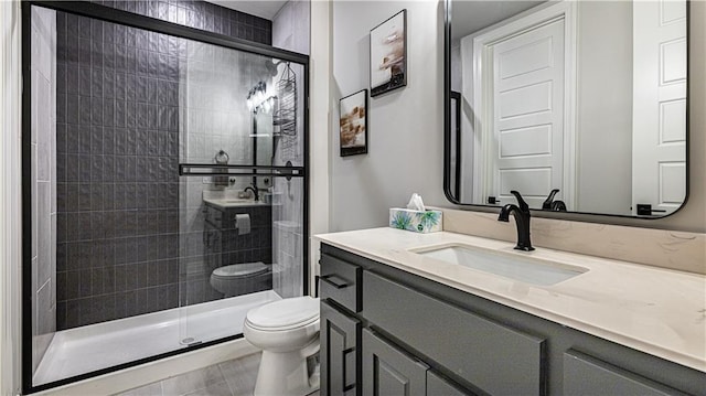 bathroom featuring vanity, toilet, tile patterned floors, and a shower with shower door