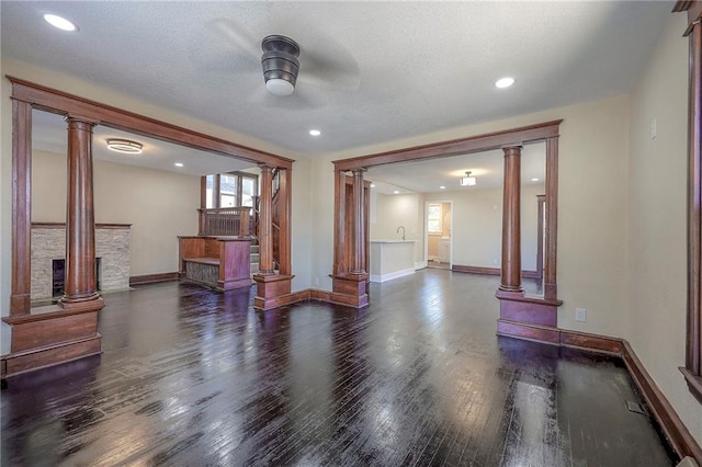 unfurnished room featuring a textured ceiling, ceiling fan, dark hardwood / wood-style flooring, and ornate columns