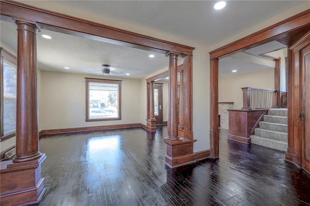 unfurnished room with a textured ceiling, decorative columns, and dark hardwood / wood-style floors