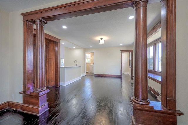 spare room featuring dark hardwood / wood-style flooring and ornate columns