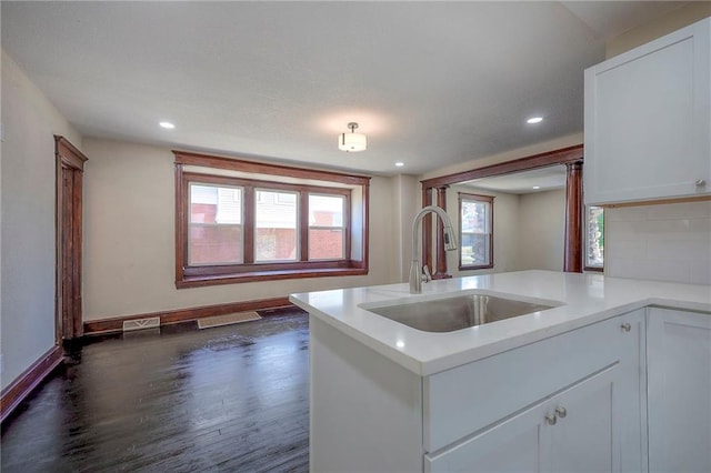 kitchen with dark wood-type flooring, white cabinets, backsplash, and sink