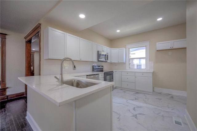 kitchen featuring stainless steel appliances, sink, kitchen peninsula, light wood-type flooring, and white cabinets