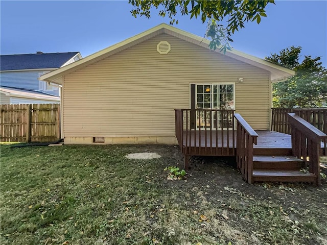 back of house featuring a deck and a lawn