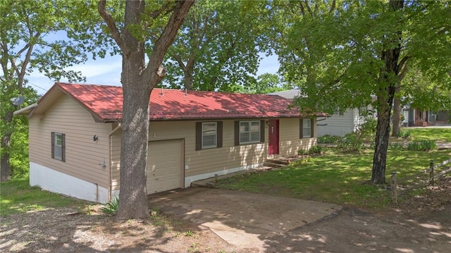 ranch-style house with metal roof, a front yard, a garage, and concrete driveway