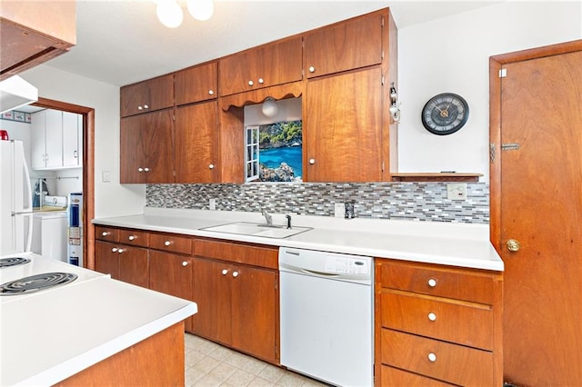 kitchen with light countertops, backsplash, a sink, brown cabinets, and white appliances