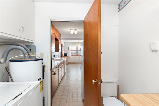 laundry room featuring washer / clothes dryer, water heater, sink, and a textured ceiling