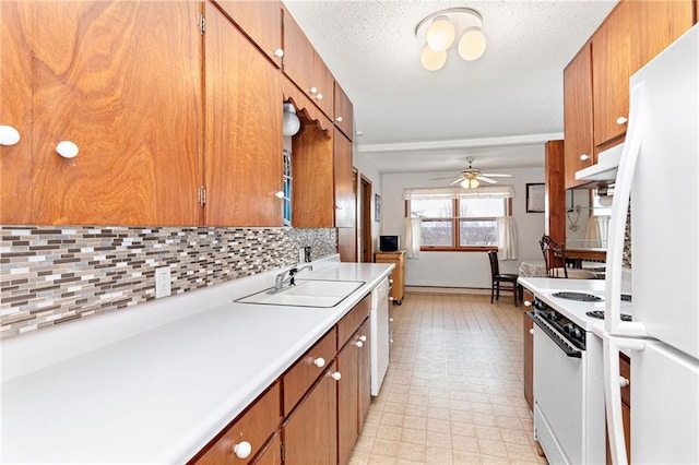 kitchen featuring light countertops, a sink, brown cabinetry, and white appliances