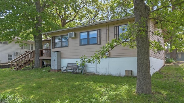 rear view of property featuring a wall unit AC, a yard, and a deck