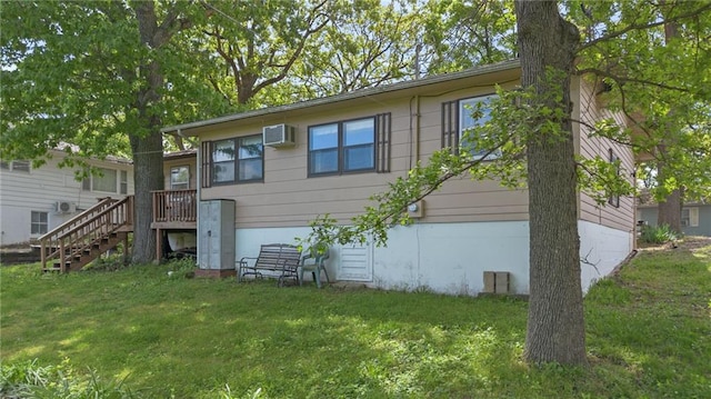 back of house with a wall mounted AC, stairs, and a lawn