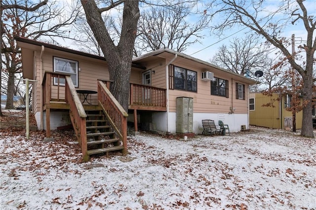 snow covered property with a wall mounted AC, stairway, and a deck