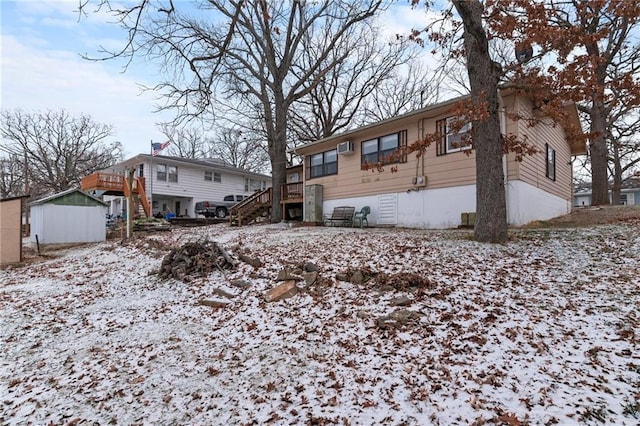 snow covered rear of property featuring a storage shed