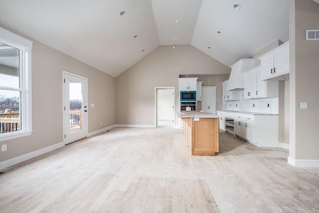 kitchen featuring vaulted ceiling, a kitchen island, black appliances, light hardwood / wood-style floors, and white cabinetry