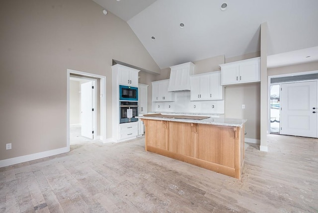 kitchen with wall oven, black microwave, a large island, and white cabinets