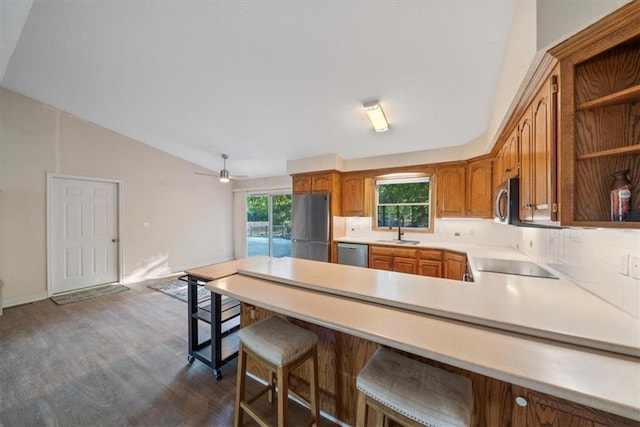 kitchen with stainless steel appliances, sink, kitchen peninsula, ceiling fan, and a breakfast bar