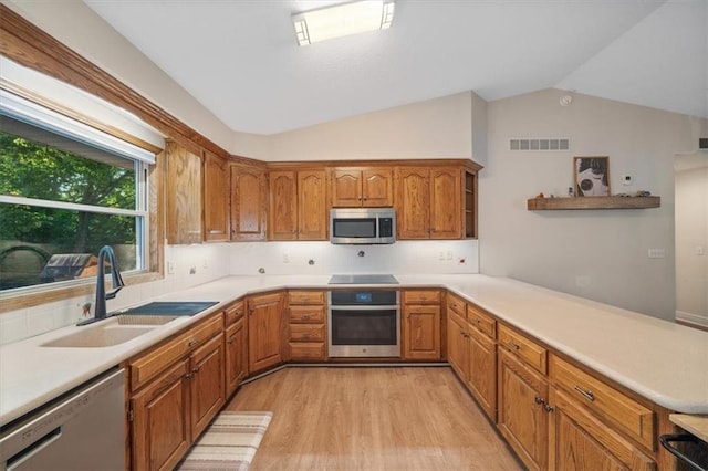 kitchen featuring kitchen peninsula, sink, appliances with stainless steel finishes, lofted ceiling, and light hardwood / wood-style floors