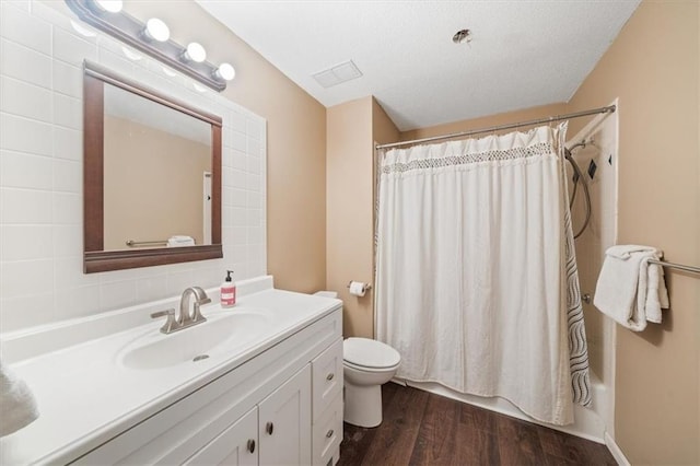 full bathroom with toilet, vanity, a textured ceiling, wood-type flooring, and shower / tub combo