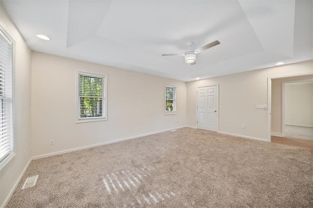 carpeted spare room featuring ceiling fan and a raised ceiling