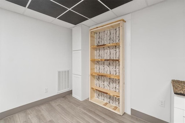 spare room featuring light hardwood / wood-style floors and a drop ceiling