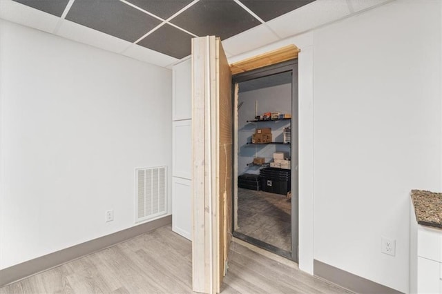 interior space with light wood-type flooring and a paneled ceiling