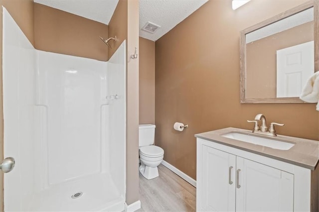 bathroom featuring a textured ceiling, vanity, wood-type flooring, walk in shower, and toilet